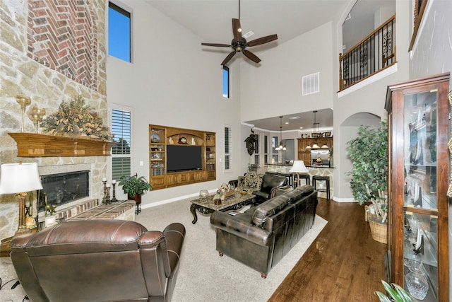 2401 Portwood Way, Fort Worth, TX 76179 - living room featuring ceiling fan, a towering ceiling, a stone fireplace, baseboards, and wood finished floors