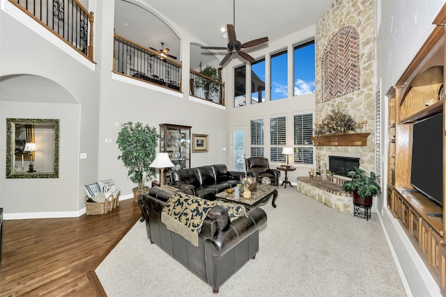 2401 Portwood Way, Fort Worth, TX 76179 - living area featuring a fireplace, ceiling fan, a towering ceiling, wood finished floors, and baseboards