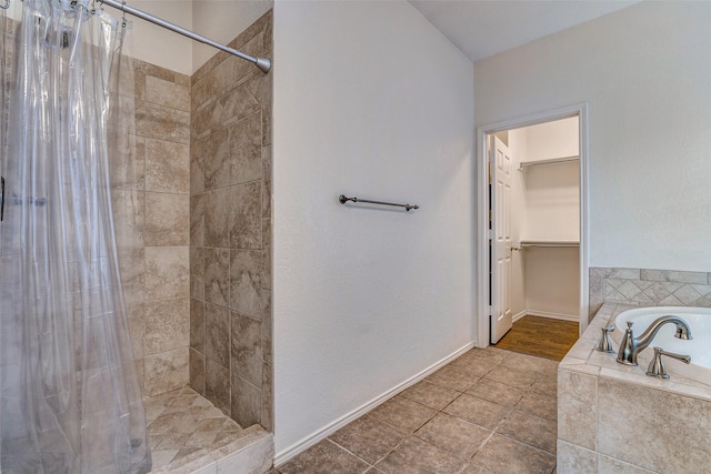 bathroom with a shower stall, a garden tub, a spacious closet, and tile patterned flooring