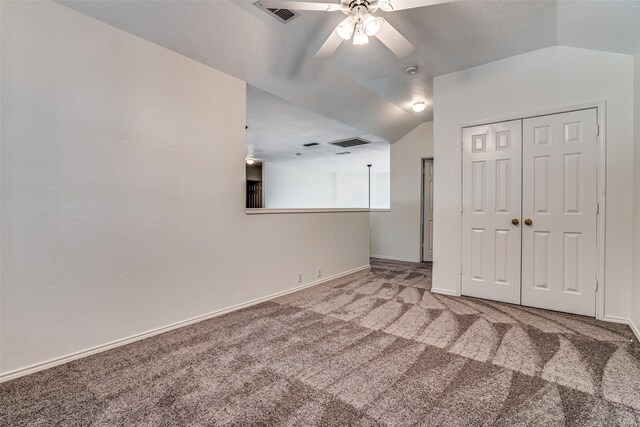 unfurnished bedroom featuring carpet floors, vaulted ceiling, baseboards, a closet, and ceiling fan