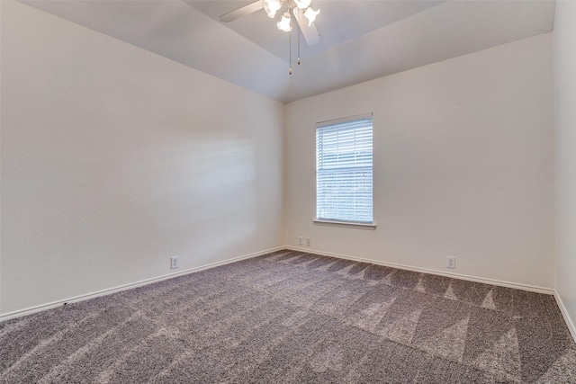 spare room featuring dark carpet, a ceiling fan, baseboards, and vaulted ceiling