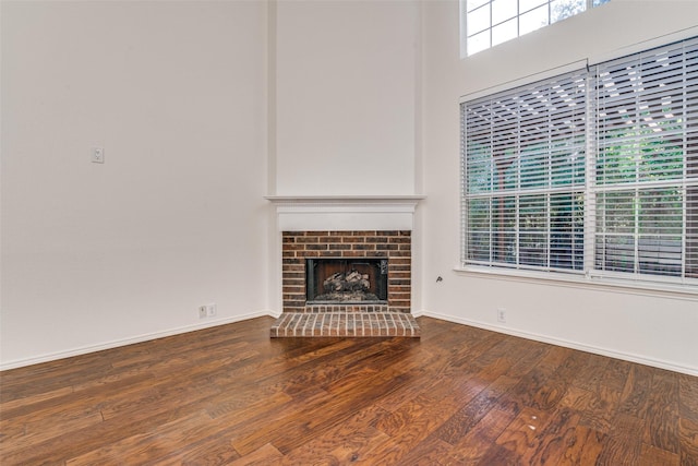 unfurnished living room featuring wood finished floors, baseboards, and a fireplace