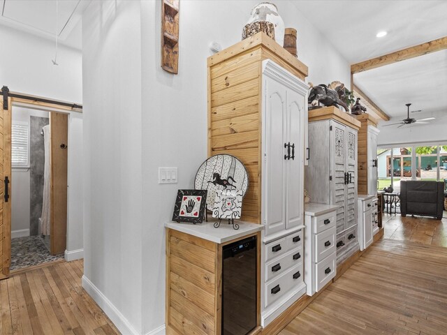 corridor featuring attic access, beverage cooler, light wood-style floors, baseboards, and recessed lighting