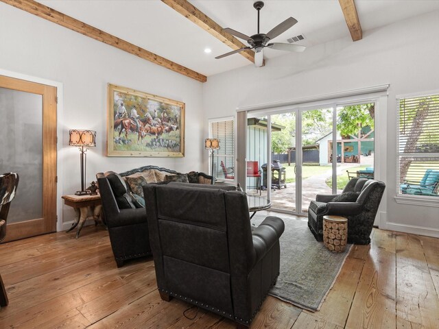 living area featuring beamed ceiling, healthy amount of natural light, hardwood / wood-style flooring, a ceiling fan, and baseboards