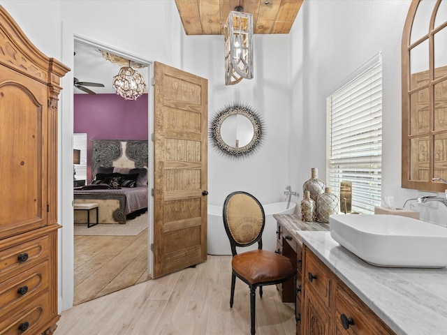 ensuite bathroom featuring wood finished floors, vanity, a freestanding tub, a chandelier, and wooden ceiling