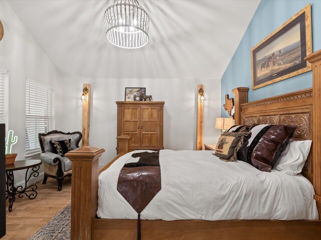 bedroom featuring lofted ceiling, wood finished floors, and a chandelier