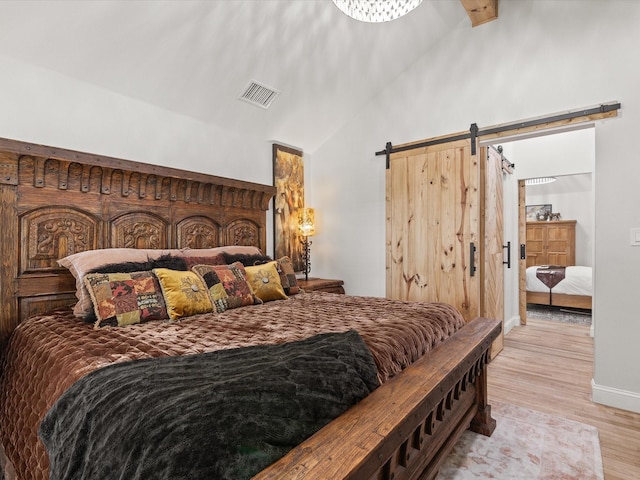 bedroom with a barn door, light wood-style flooring, baseboards, and high vaulted ceiling