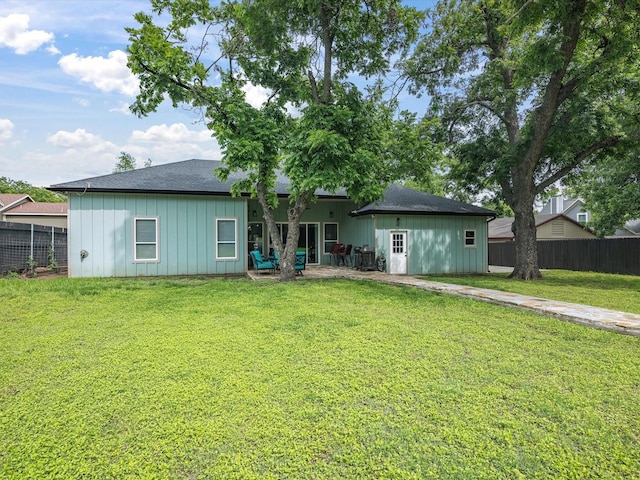 back of property with board and batten siding, a shingled roof, and a patio area