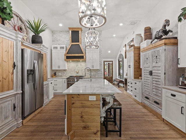 kitchen featuring stainless steel appliances, tasteful backsplash, a breakfast bar area, light stone countertops, and a chandelier