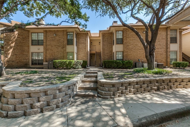 townhome / multi-family property with brick siding and central AC unit