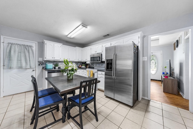 400 Houston St, Sulphur Springs, TX 75482 - kitchen with stainless steel appliances, white cabinets, dark countertops, and light tile patterned floors
