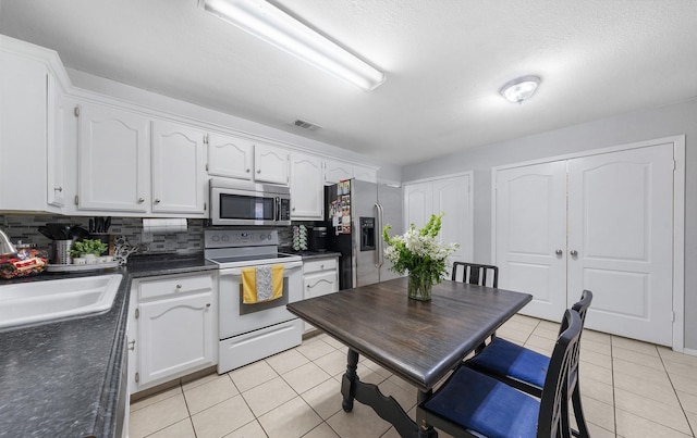 400 Houston St, Sulphur Springs, TX 75482 - kitchen featuring appliances with stainless steel finishes, dark countertops, a sink, and white cabinets