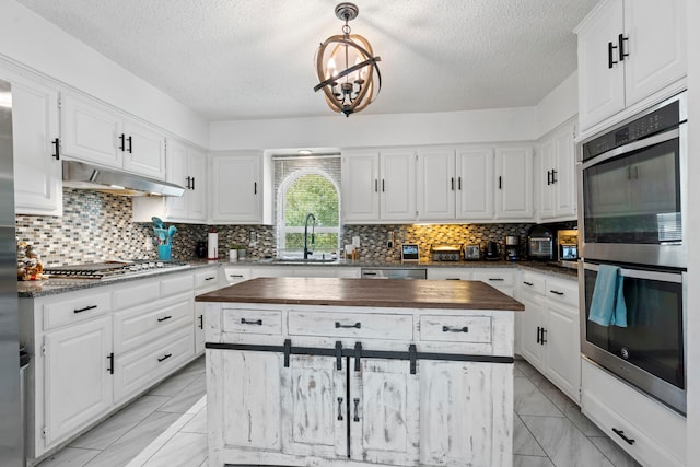 1426 Northridge Dr, Carrollton, TX 75006 - kitchen with appliances with stainless steel finishes, a sink, under cabinet range hood, butcher block counters, and light marble finish flooring