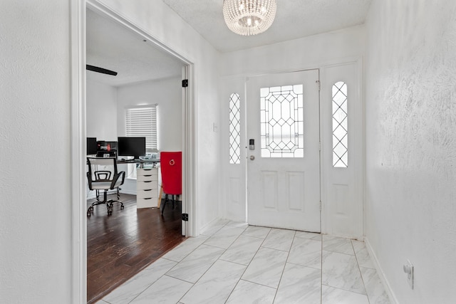 1426 Northridge Dr, Carrollton, TX 75006 - entryway featuring a chandelier, a textured wall, baseboards, and light marble finish flooring