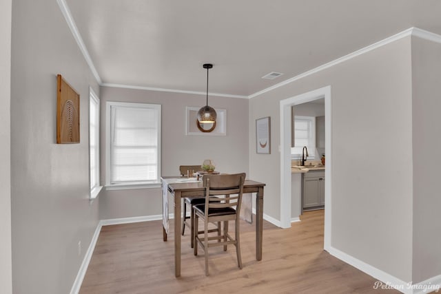 dining room featuring light wood-type flooring, crown molding, and baseboards