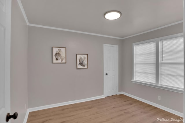 unfurnished room with light wood-type flooring, crown molding, and baseboards