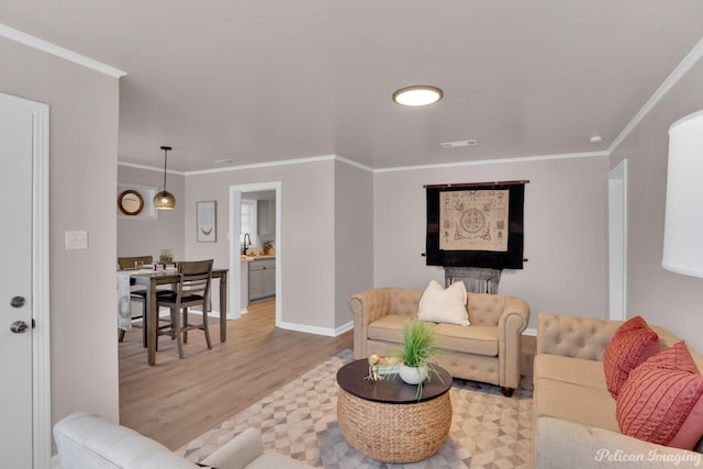 living area featuring light wood-style flooring, ornamental molding, and baseboards