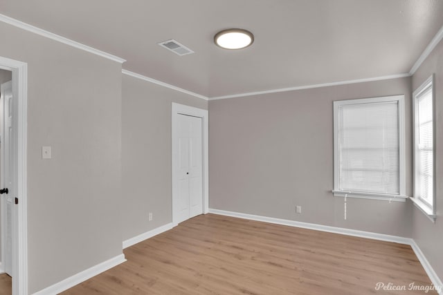 unfurnished room featuring light wood finished floors, ornamental molding, and baseboards