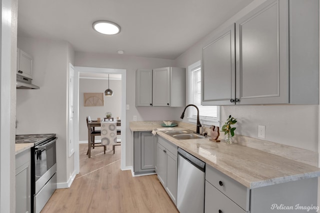 kitchen with stainless steel appliances, under cabinet range hood, a sink, gray cabinets, and light wood finished floors