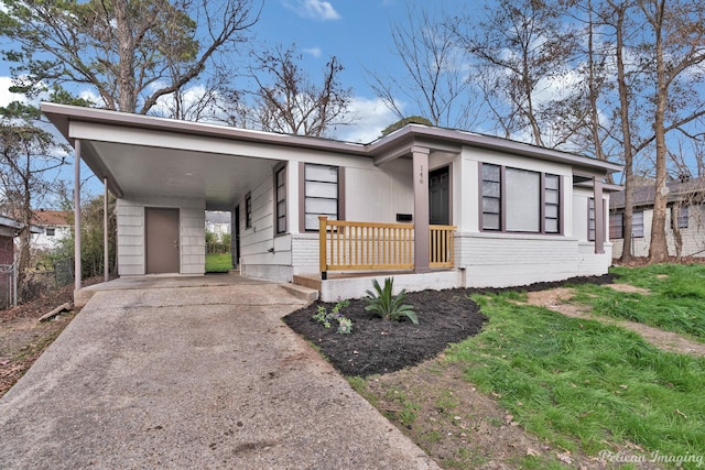 mid-century home with concrete driveway and a carport