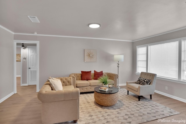 living area with ornamental molding, wood finished floors, baseboards, and plenty of natural light