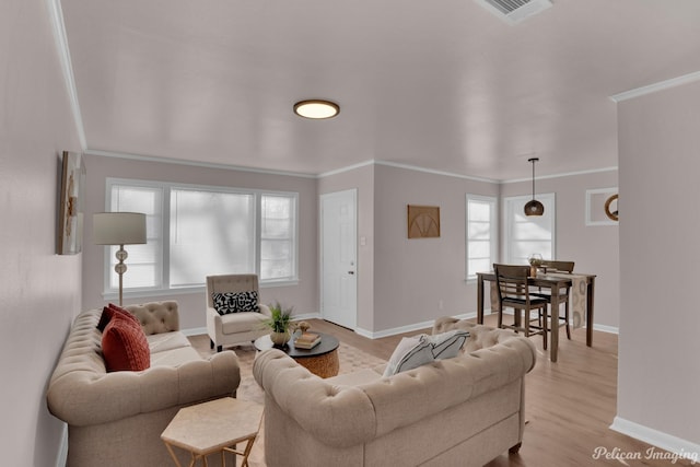 living room with baseboards, ornamental molding, and light wood finished floors