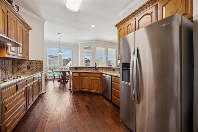 kitchen with appliances with stainless steel finishes, ornamental molding, a peninsula, a sink, and brown cabinets