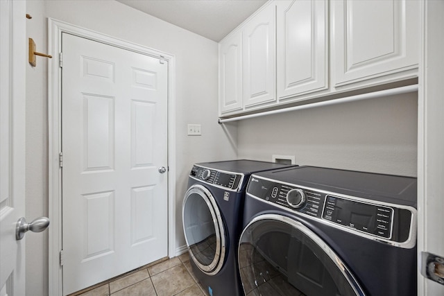 washroom with independent washer and dryer, cabinet space, and light tile patterned flooring