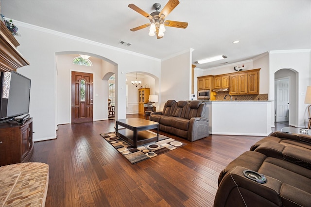 living room featuring arched walkways, a ceiling fan, crown molding, dark wood finished floors, and recessed lighting