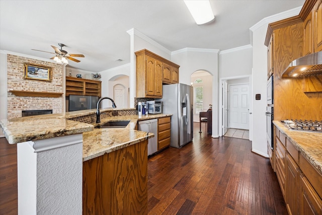 kitchen with appliances with stainless steel finishes, arched walkways, a sink, ceiling fan, and crown molding