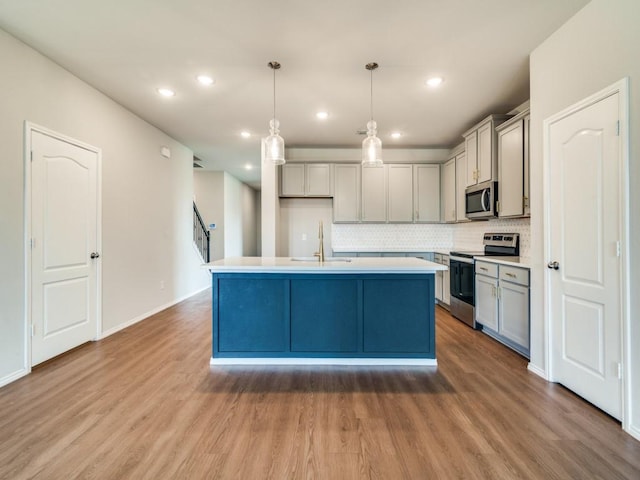3305 Brentwood Cv, Forney, TX 75126 - kitchen with stainless steel appliances, a sink, wood finished floors, gray cabinetry, and recessed lighting