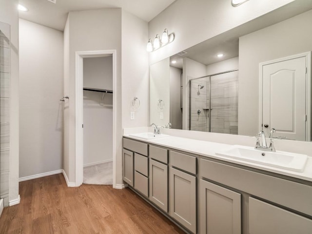 3305 Brentwood Cv, Forney, TX 75126 - bathroom featuring a shower stall, wood finished floors, double vanity, a walk in closet, and baseboards