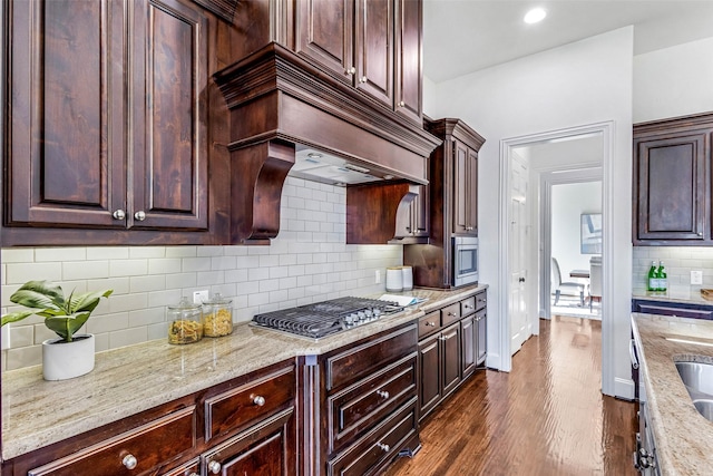901 Clear Water Dr, Allen, TX 75013 - kitchen featuring appliances with stainless steel finishes, tasteful backsplash, light stone counters, dark wood-style flooring, and dark brown cabinetry