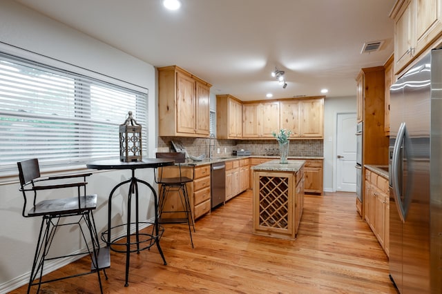 5820 Forest Ln, Dallas, TX 75230 - kitchen featuring stainless steel appliances, light wood-type flooring, light brown cabinetry, a kitchen island, and tasteful backsplash