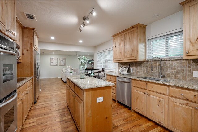 5820 Forest Ln, Dallas, TX 75230 - kitchen featuring appliances with stainless steel finishes, a center island, a sink, light wood-type flooring, and recessed lighting