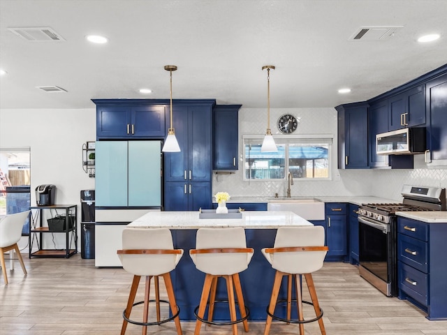 3939 Ermis St, Haltom City, TX 76111 - kitchen featuring appliances with stainless steel finishes, blue cabinets, a breakfast bar area, light wood finished floors, and tasteful backsplash