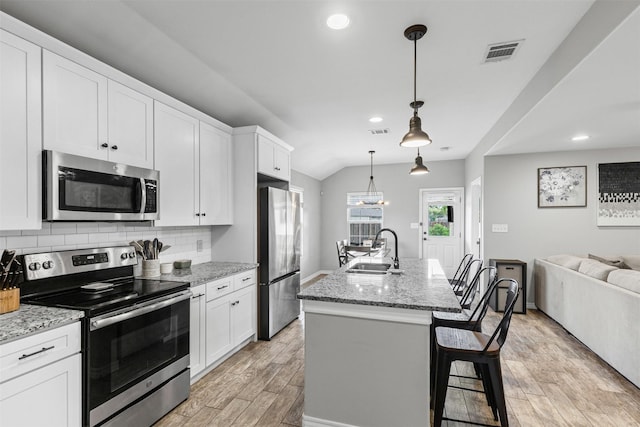 2104 Shane Ave, Fort Worth, TX 76134 - kitchen featuring stainless steel appliances, a sink, light wood-type flooring, open floor plan, and white cabinets