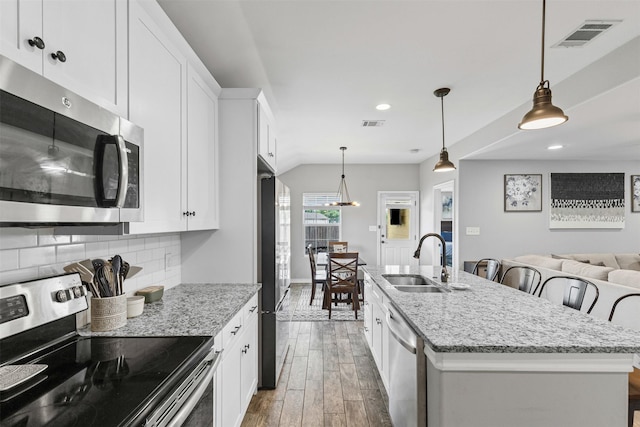 2104 Shane Ave, Fort Worth, TX 76134 - kitchen with stainless steel appliances, a sink, wood finished floors, decorative backsplash, and white cabinetry