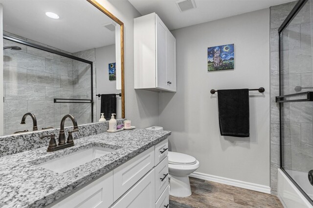 2104 Shane Ave, Fort Worth, TX 76134 - bathroom with wood finished floors, baseboards, vanity, toilet, and enclosed tub / shower combo