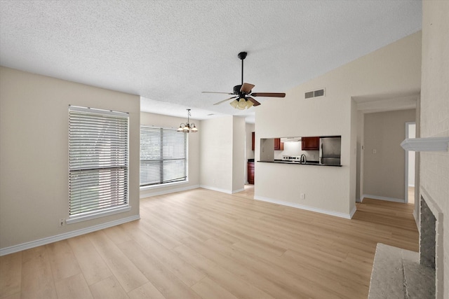 1204 Calico Ln Unit 720, Arlington, TX 76011 - unfurnished living room featuring a fireplace, a chandelier, light wood finished floors, a textured ceiling, and ceiling fan