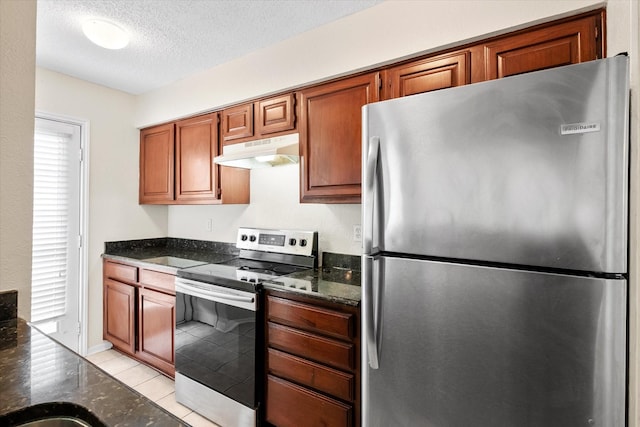 1204 Calico Ln Unit 720, Arlington, TX 76011 - kitchen with appliances with stainless steel finishes, under cabinet range hood, light tile patterned flooring, dark stone countertops, and a textured ceiling