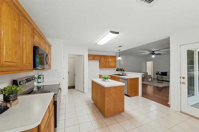 218 Whispering Dell Ln, Weatherford, TX 76085 - kitchen with stainless steel appliances, a sink, a center island, brown cabinets, and a peninsula