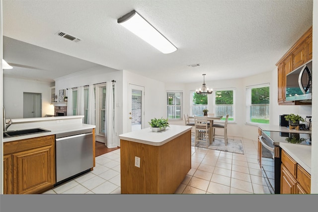 218 Whispering Dell Ln, Weatherford, TX 76085 - kitchen featuring stainless steel appliances, brown cabinetry, light tile patterned floors, and a textured ceiling