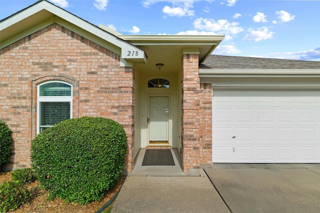 218 Whispering Dell Ln, Weatherford, TX 76085 - view of exterior entry featuring brick siding, concrete driveway, an attached garage, and roof with shingles