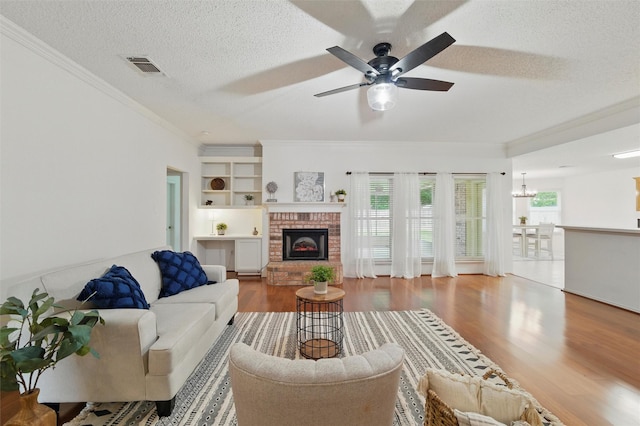 218 Whispering Dell Ln, Weatherford, TX 76085 - living room with crown molding, wood finished floors, a textured ceiling, a brick fireplace, and ceiling fan