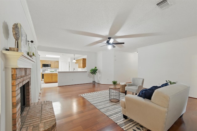 218 Whispering Dell Ln, Weatherford, TX 76085 - living room featuring ornamental molding, a ceiling fan, light wood-style flooring, a brick fireplace, and a textured ceiling