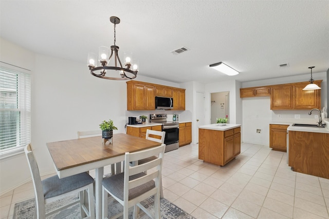 218 Whispering Dell Ln, Weatherford, TX 76085 - kitchen featuring stainless steel appliances, a sink, brown cabinetry, a chandelier, and a textured ceiling