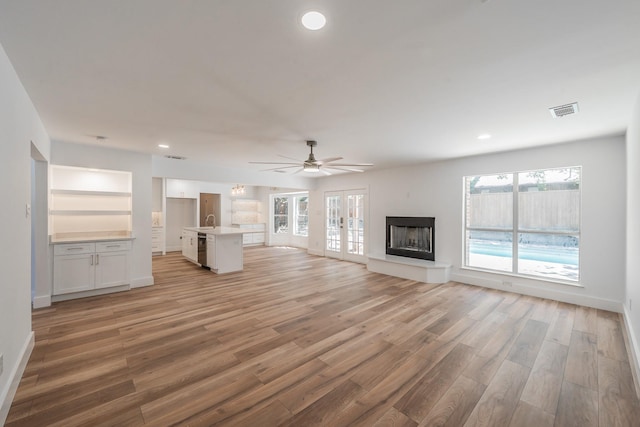 2815 Perkins Rd, Arlington, TX 76016 - unfurnished living room featuring light wood-style flooring, healthy amount of natural light, ceiling fan, a sink, and recessed lighting