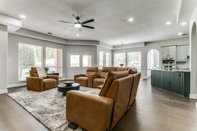 living room with arched walkways, ceiling fan, baseboards, wood finished floors, and recessed lighting