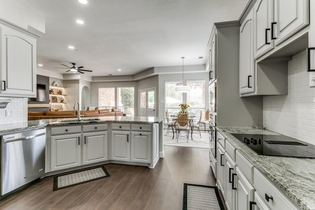 kitchen featuring appliances with stainless steel finishes, a sink, a peninsula, tasteful backsplash, and a ceiling fan